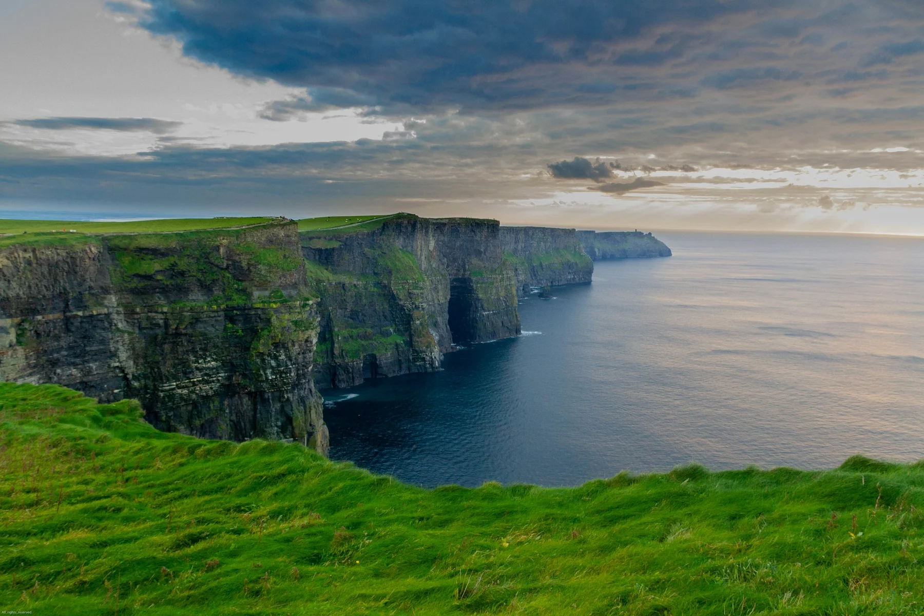 Atlantic cliffs and green fields at the Cliffs of Moher, County Clare